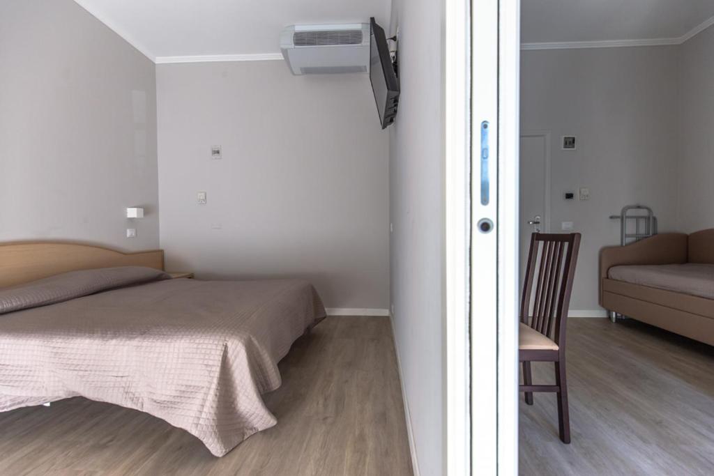 een slaapkamer met een bed, een stoel en een bank bij Hotel Susy in Rimini