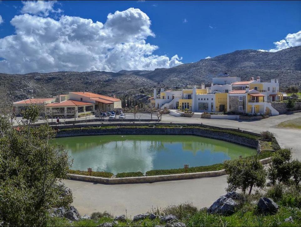 een grote waterplas voor een aantal gebouwen bij Delina Mountain Resort in Anogia