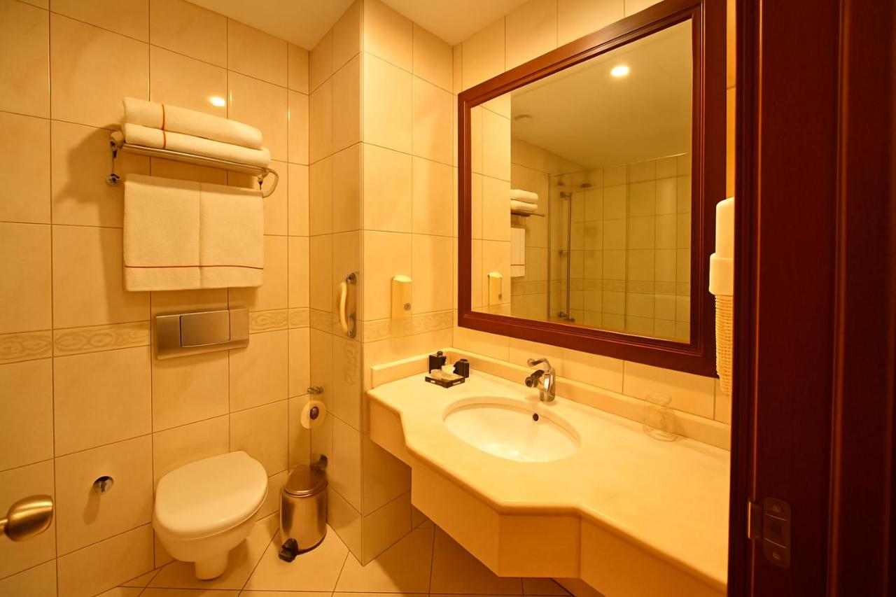 een badkamer met een wastafel, een toilet en een spiegel bij Taksim Gonen Hotel in Istanbul