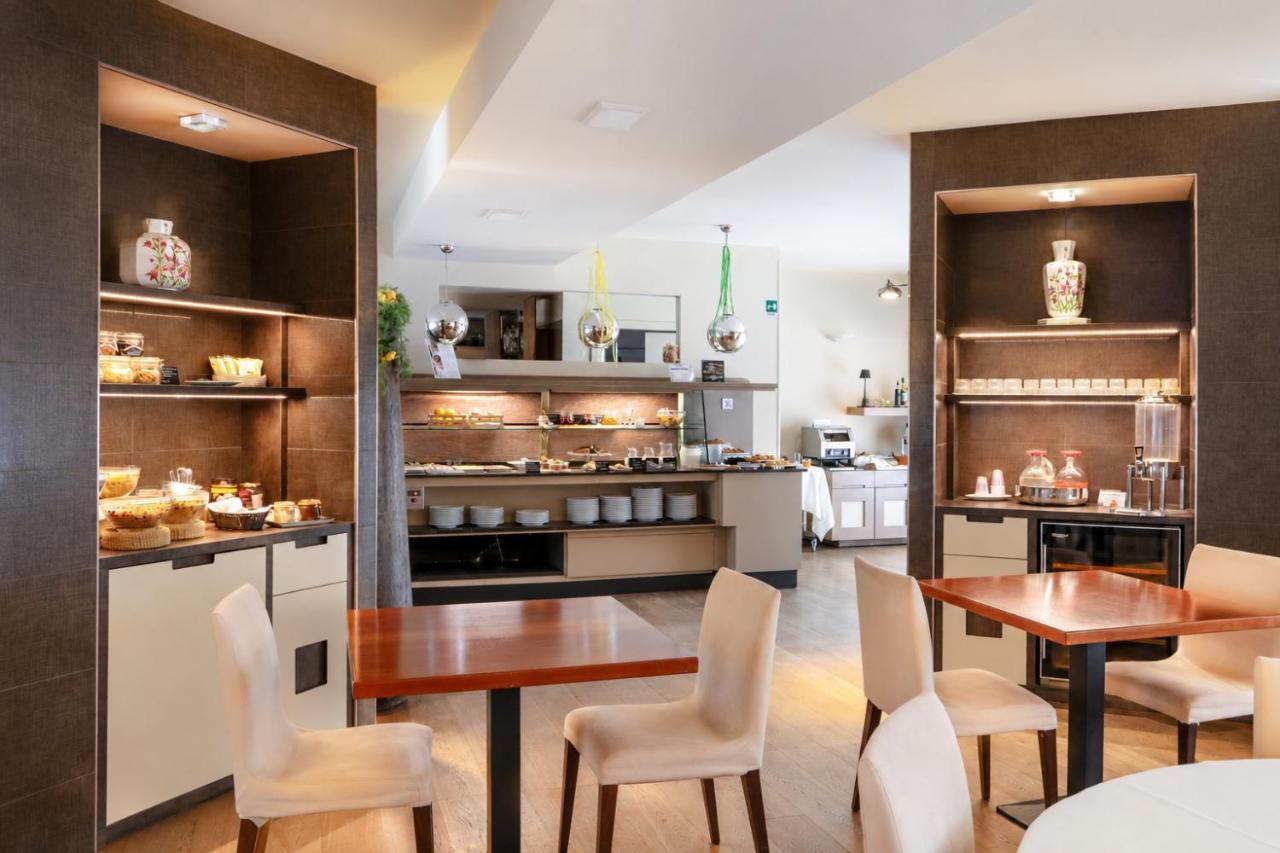 een keuken met twee tafels en stoelen en een aanrecht bij Hotel Parigi 2 & Spa in Dalmine