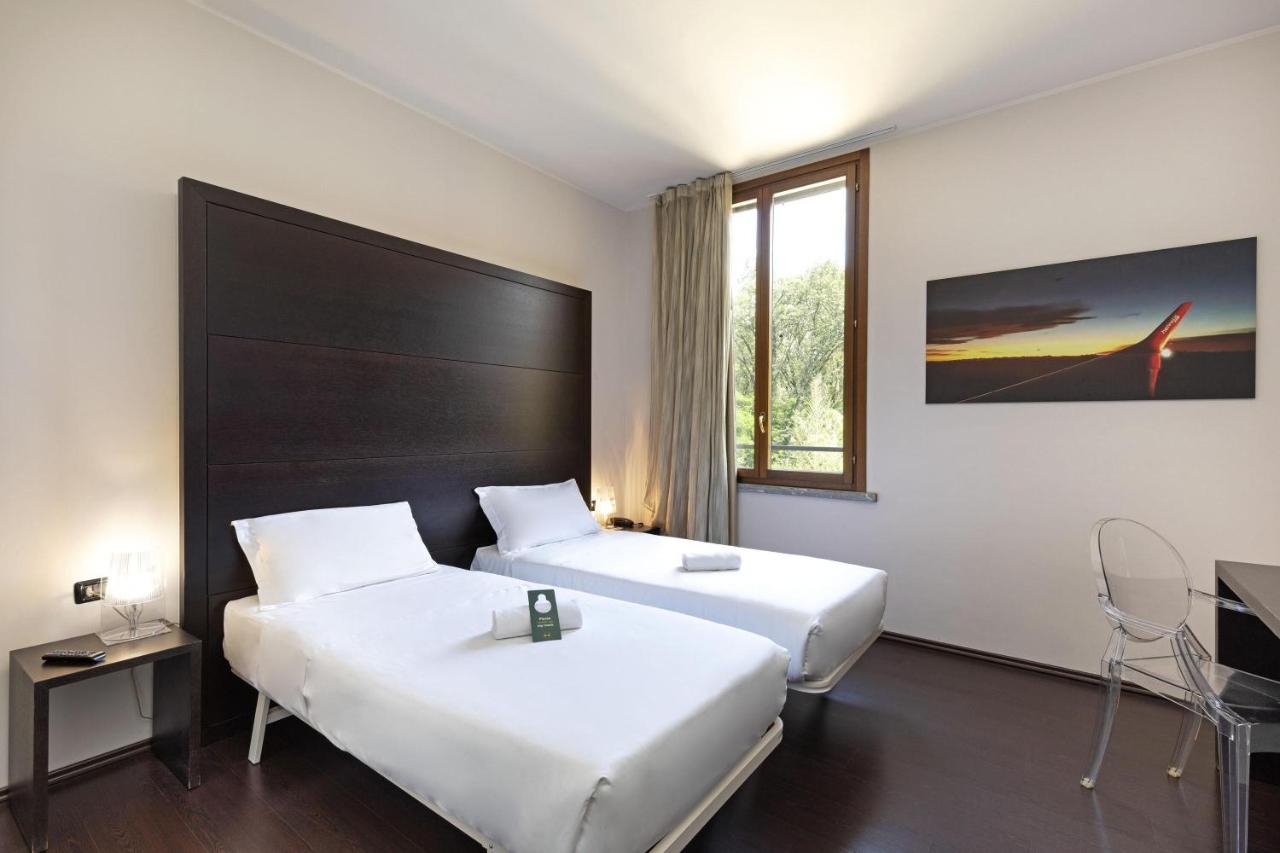 een hotelkamer met twee bedden en een raam bij B&B HOTEL Malpensa Lago Maggiore in Vergiate