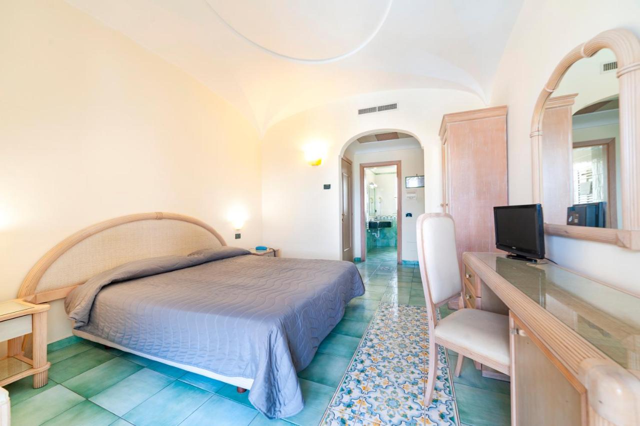 een slaapkamer met een bed en een bureau met een televisie bij Hotel Terme Don Pepe in Lacco Ameno