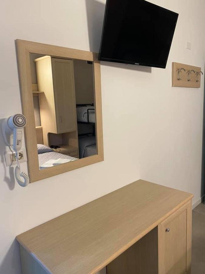 een spiegel aan de muur met een tafel en een tv bij Hotel Rex in Lido di Savio