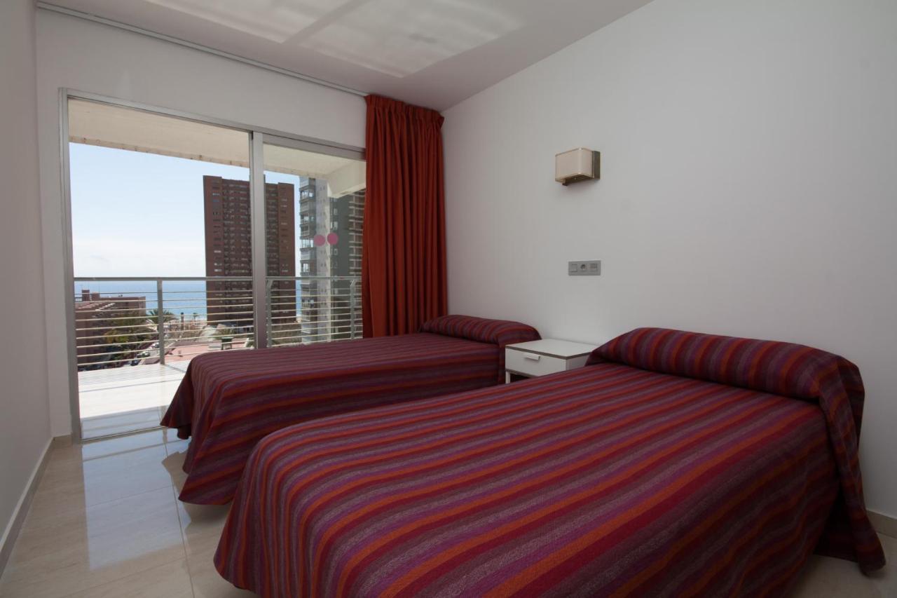 een hotelkamer met twee bedden en een groot raam bij Apartamentos Niza in Benidorm