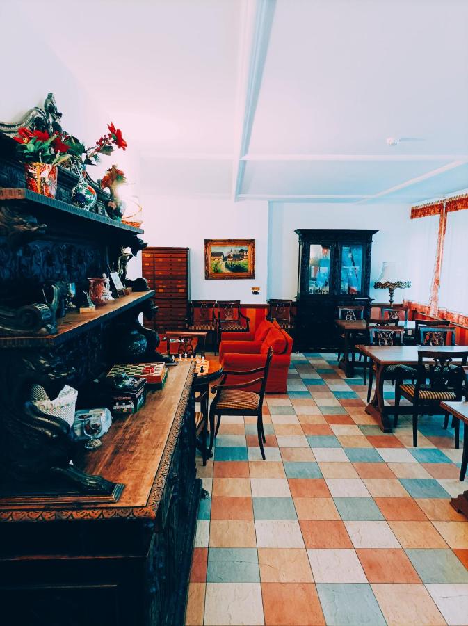 een woonkamer met een open haard en tafels en stoelen bij IHR Hotel Villa Emma in Canazei