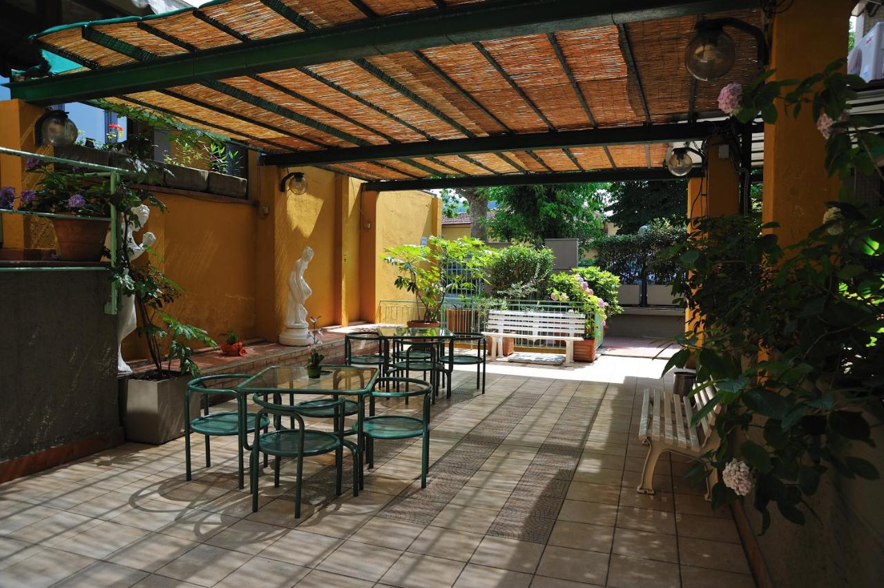 een terras met tafels en stoelen onder een houten pergola bij Hotel Salus in Montecatini Terme