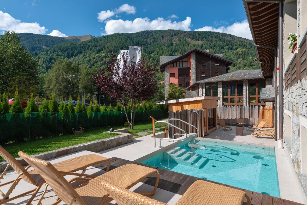 een patio met een zwembad en stoelen en een huis bij Blu Hotel Acquaseria in Ponte di Legno