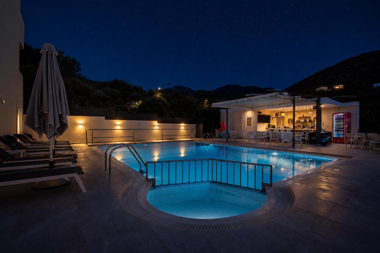 een zwembad 's nachts met een parasol bij Elpis Studio Apartments in Balíon