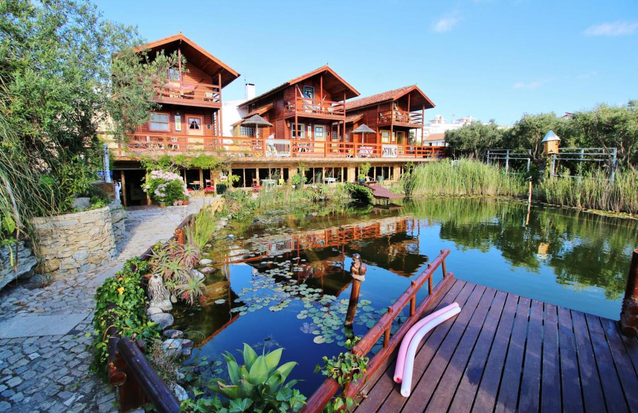 een groot houten huis met een vijver ervoor bij Villa Ana Margarida by Nature in Ericeira