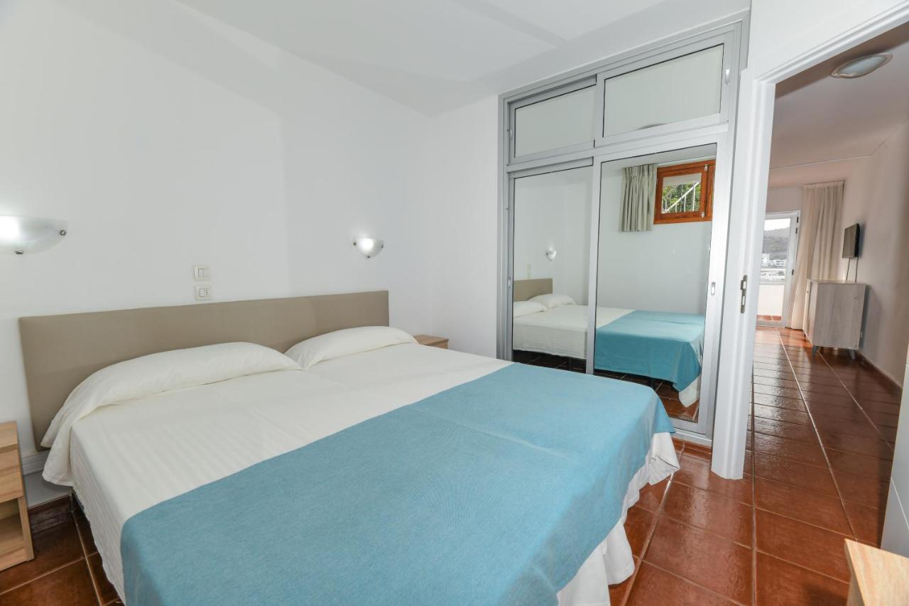 een slaapkamer met een blauw-wit bed en een spiegel bij Apartamentos LIVVO Puerto Bello in Puerto Rico de Gran Canaria
