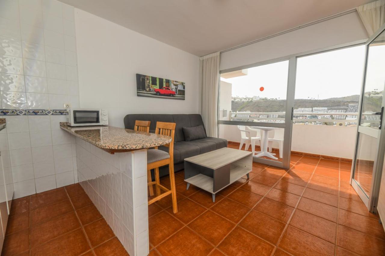 een keuken en woonkamer met een bank en een tafel bij Apartamentos LIVVO Puerto Bello in Puerto Rico de Gran Canaria