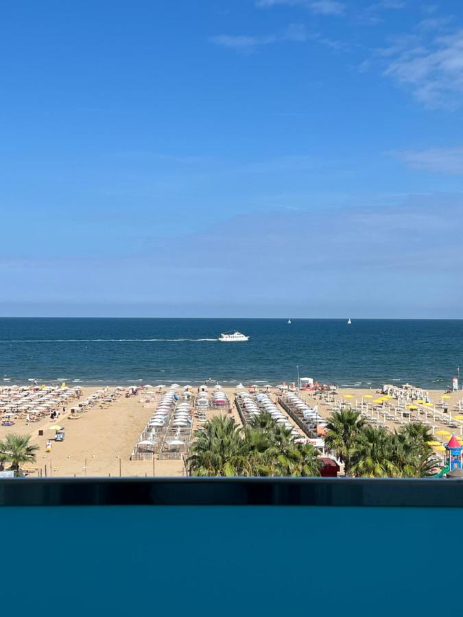 een uitzicht op een strand met een boot op de oceaan bij MoMo Seaview Hotel in Rimini