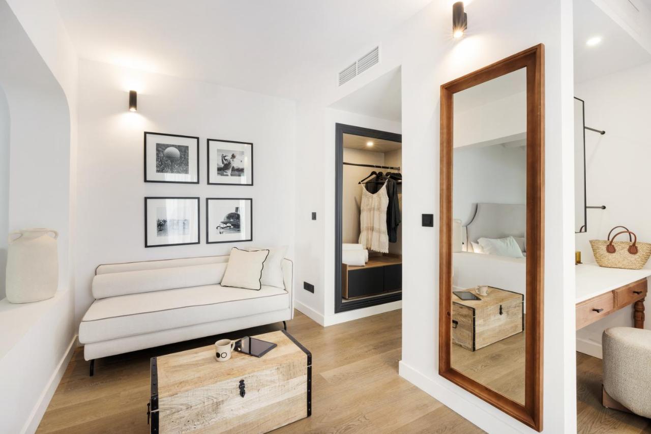 een woonkamer met een witte bank en een spiegel bij Hotel Inmood San Roque in Sotogrande