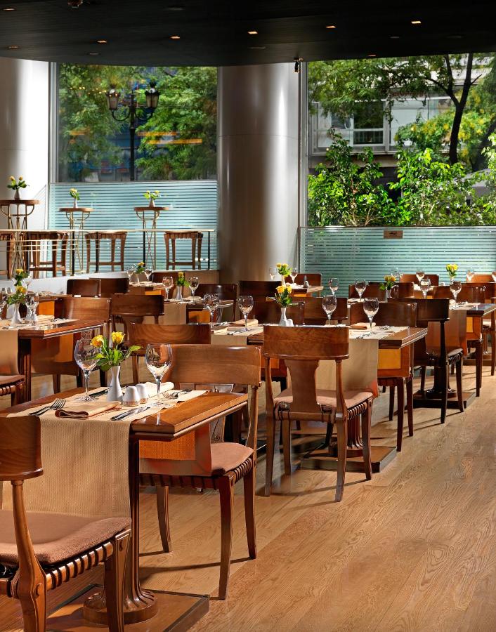 een restaurant met houten tafels en stoelen en ramen bij Titania Hotel in Athene