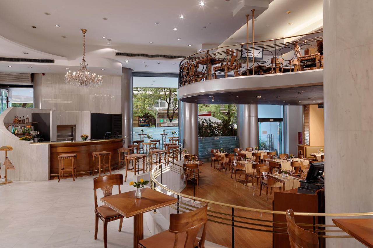 een restaurant met een aantal tafels en stoelen bij Titania Hotel in Athene