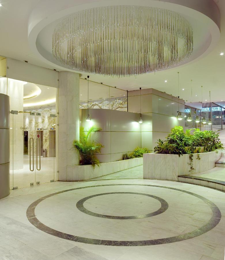 een grote lobby met een grote kroonluchter in een gebouw bij Titania Hotel in Athene