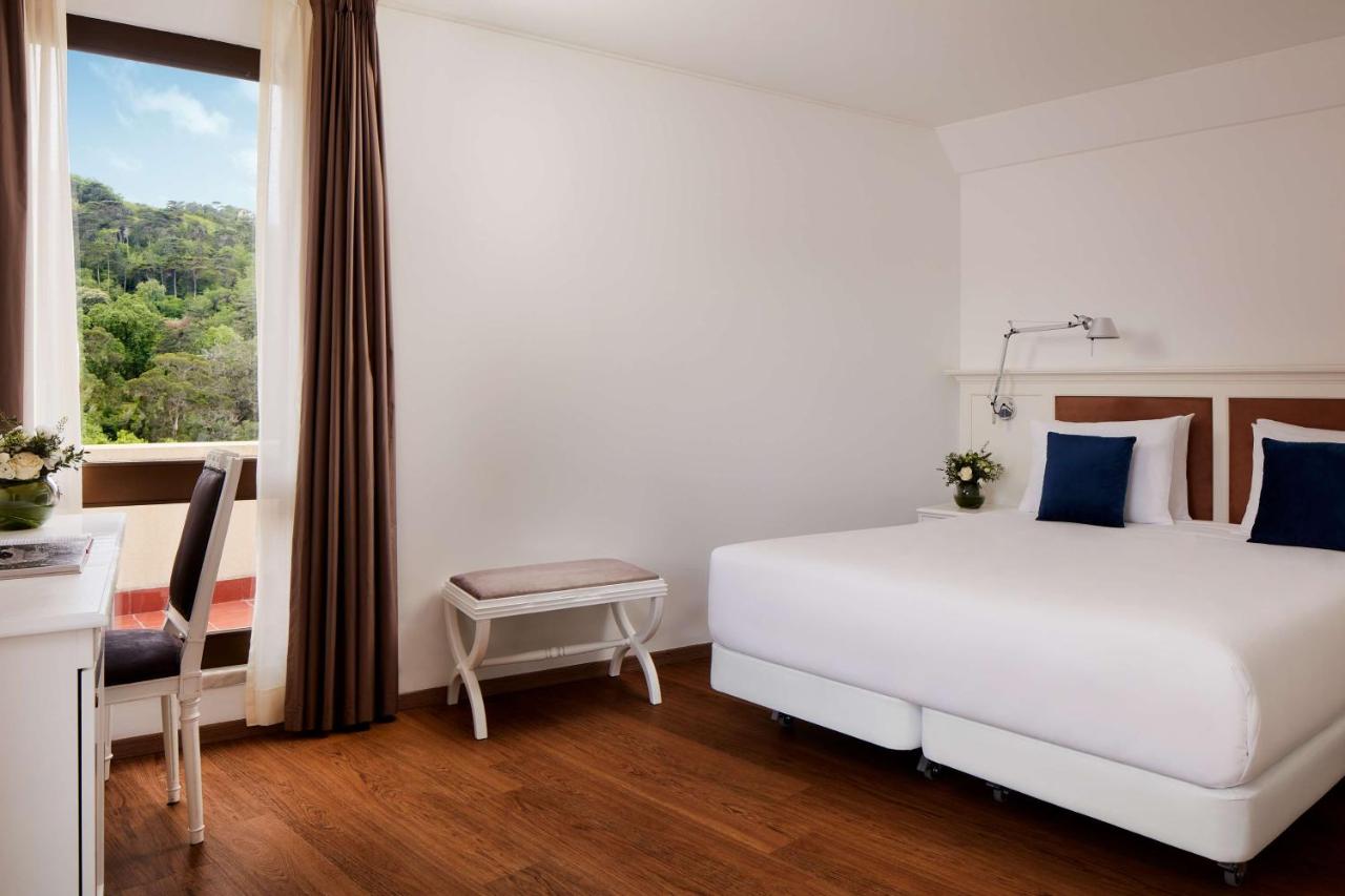 een slaapkamer met een groot wit bed en een raam bij NH Sintra Centro in Sintra