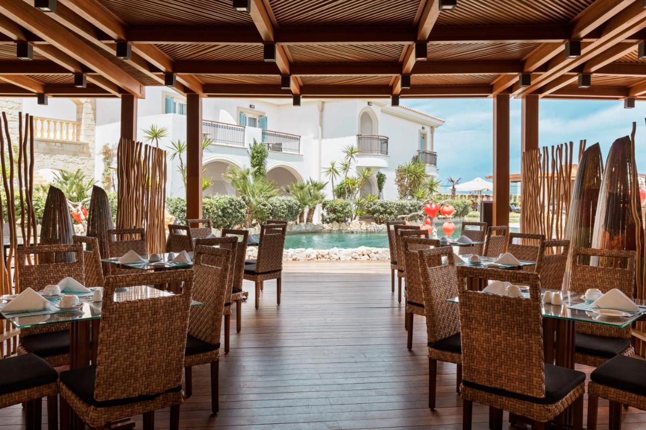 een restaurant met tafels en stoelen en een zwembad bij Mitsis Selection Laguna in Chersonissos +67 foto's