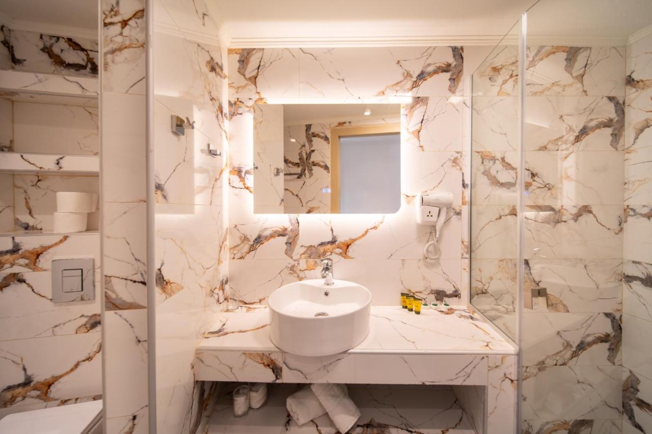 een witte badkamer met een wastafel en een spiegel bij Creta Mare Hotel in Plakias