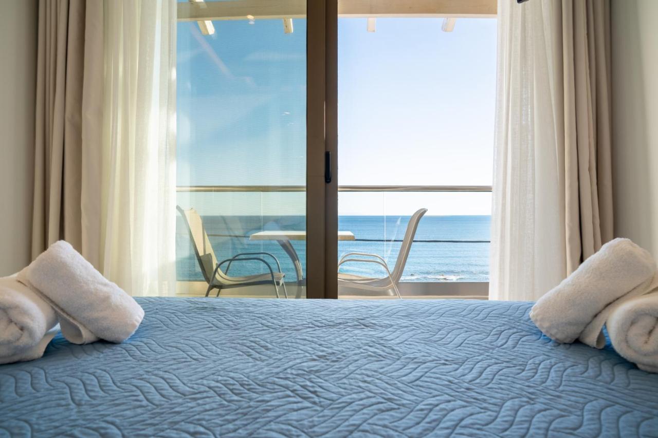 een slaapkamer met een bed en uitzicht op de oceaan bij Creta Mare Hotel in Plakias