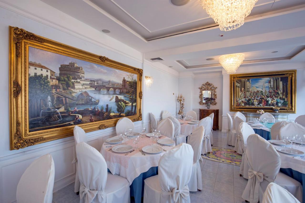 een eetkamer met witte tafels en stoelen en een schilderij bij La Panoramica Hotel in Castellammare di Stabia