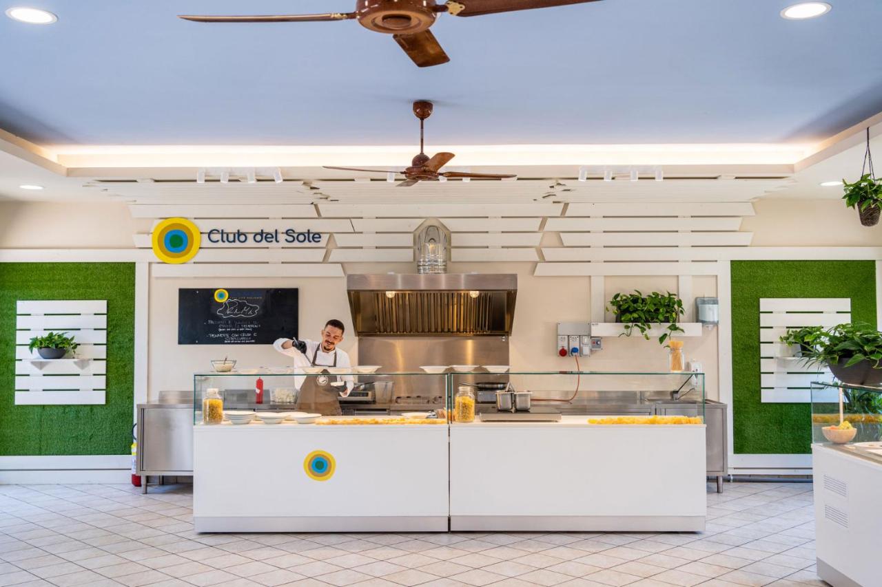 Een chef-kok die eten bereidt in een restaurantkeuken. bij Club del Sole Marina Family Resort in Punta Marina