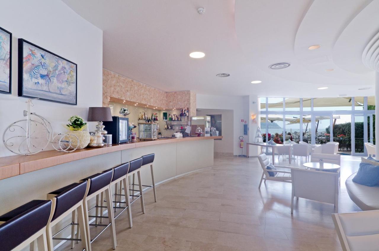een restaurant met een bar met stoelen en een tafel bij Hotel Riviera dei Fiori in San Lorenzo al Mare