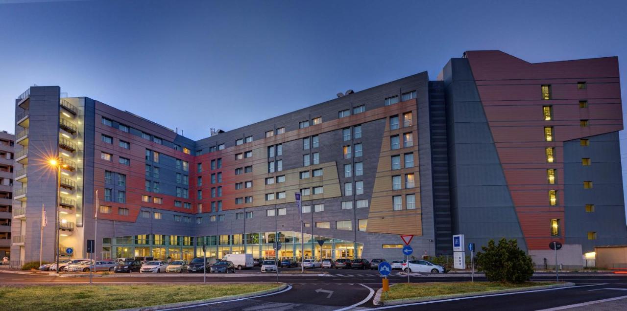 een groot gebouw met auto's ervoor geparkeerd bij iH Hotels Roma Z3 in Rome