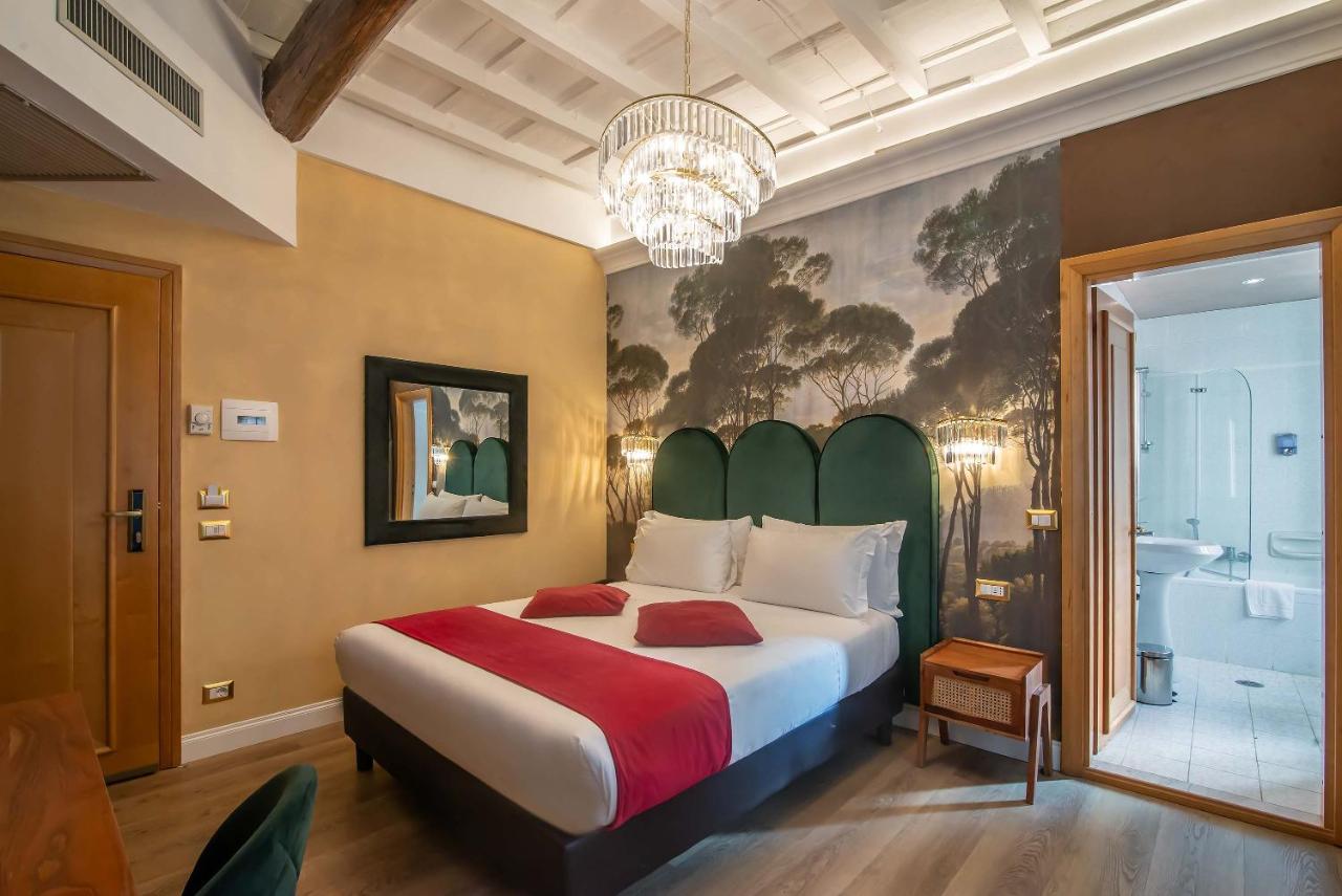 een slaapkamer met een groot bed en een kroonluchter bij Hotel Tritone in Rome