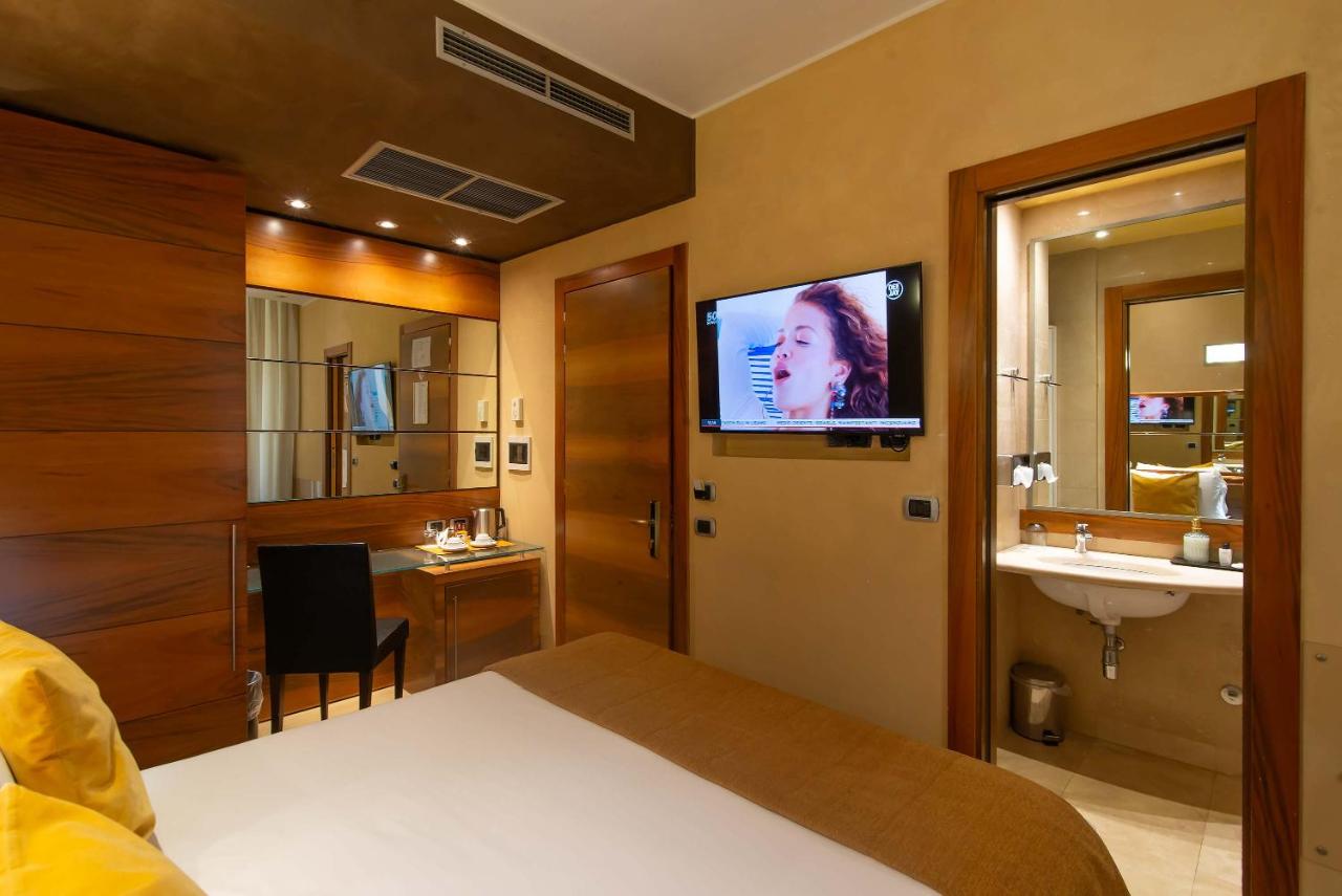 een slaapkamer met een bed en een badkamer met een televisie bij Hotel Tritone in Rome