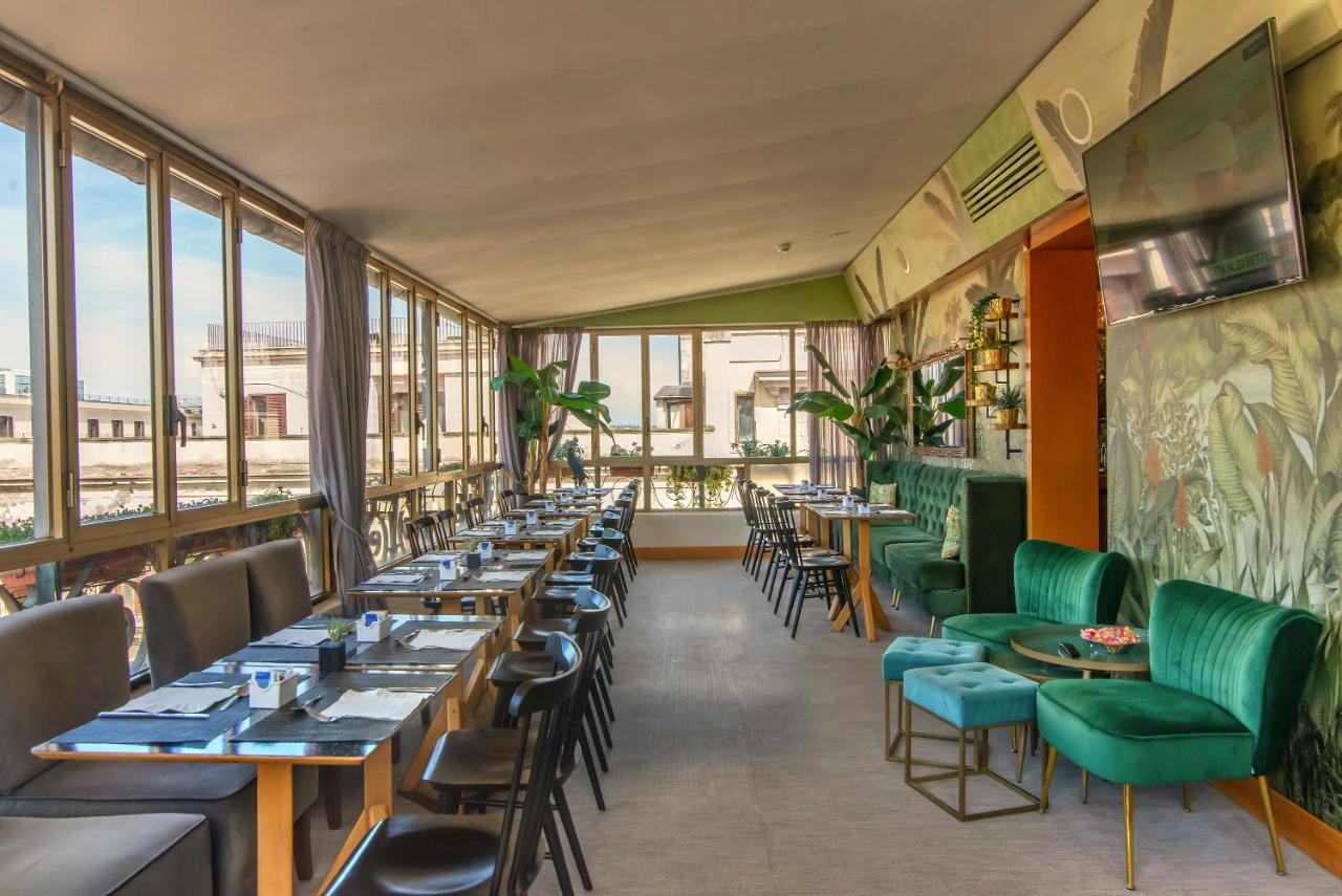 een restaurant met lange tafels en groene stoelen bij Hotel Tritone in Rome