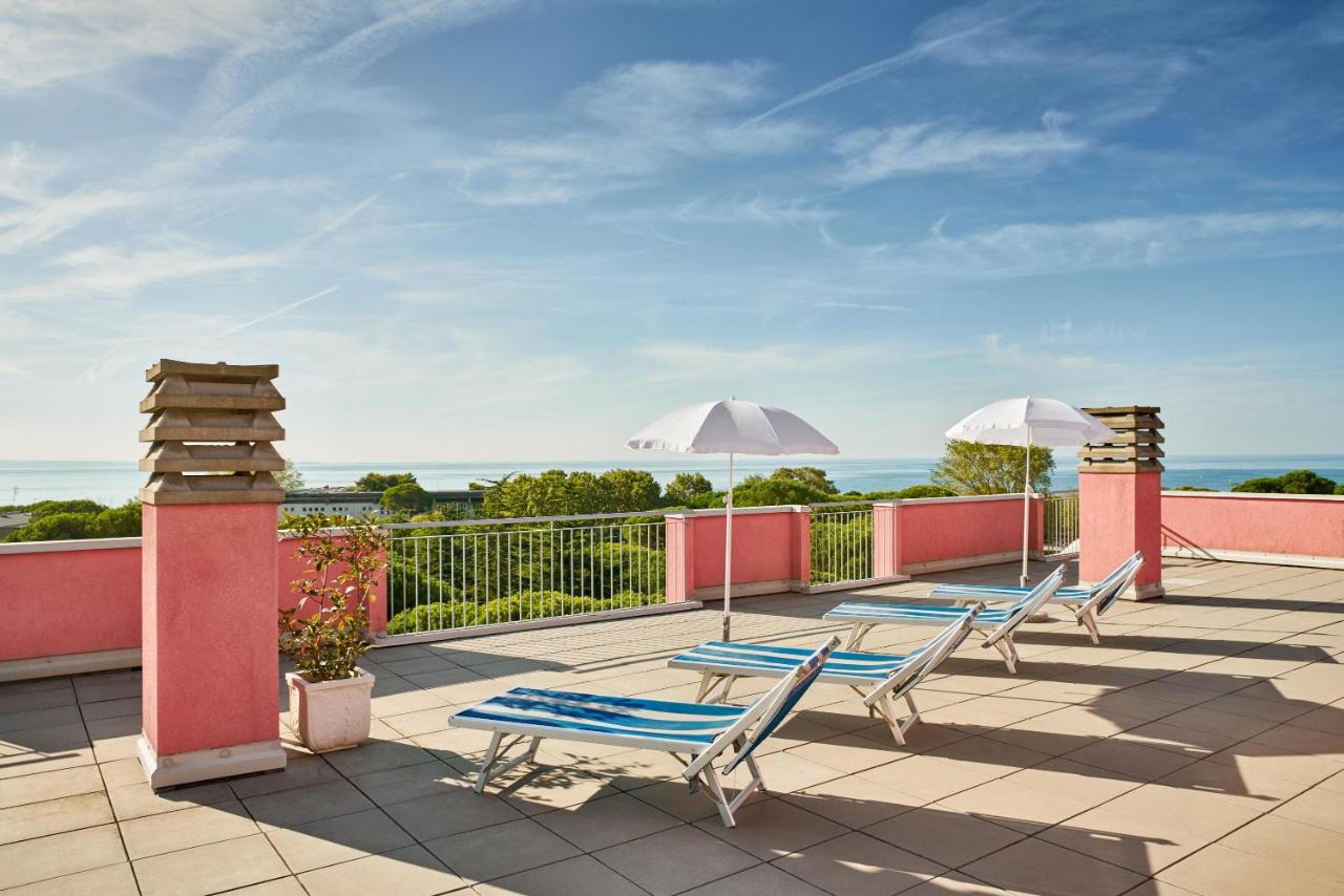 een rij ligstoelen en parasols op een terras bij Hotel Europa in Grado