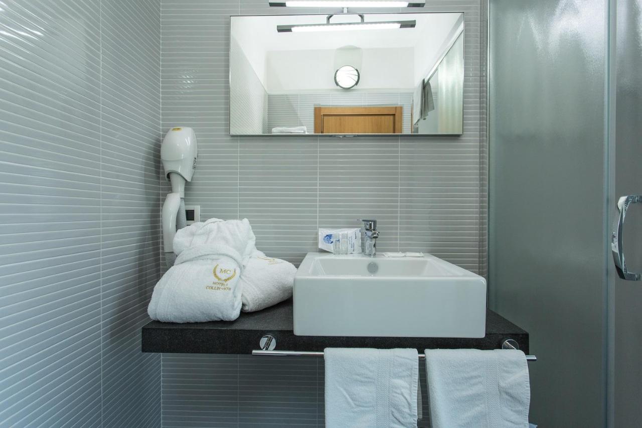 een badkamer met een wastafel, een spiegel en handdoeken bij Hotel Lalla Beauty & Relax in Cesenatico