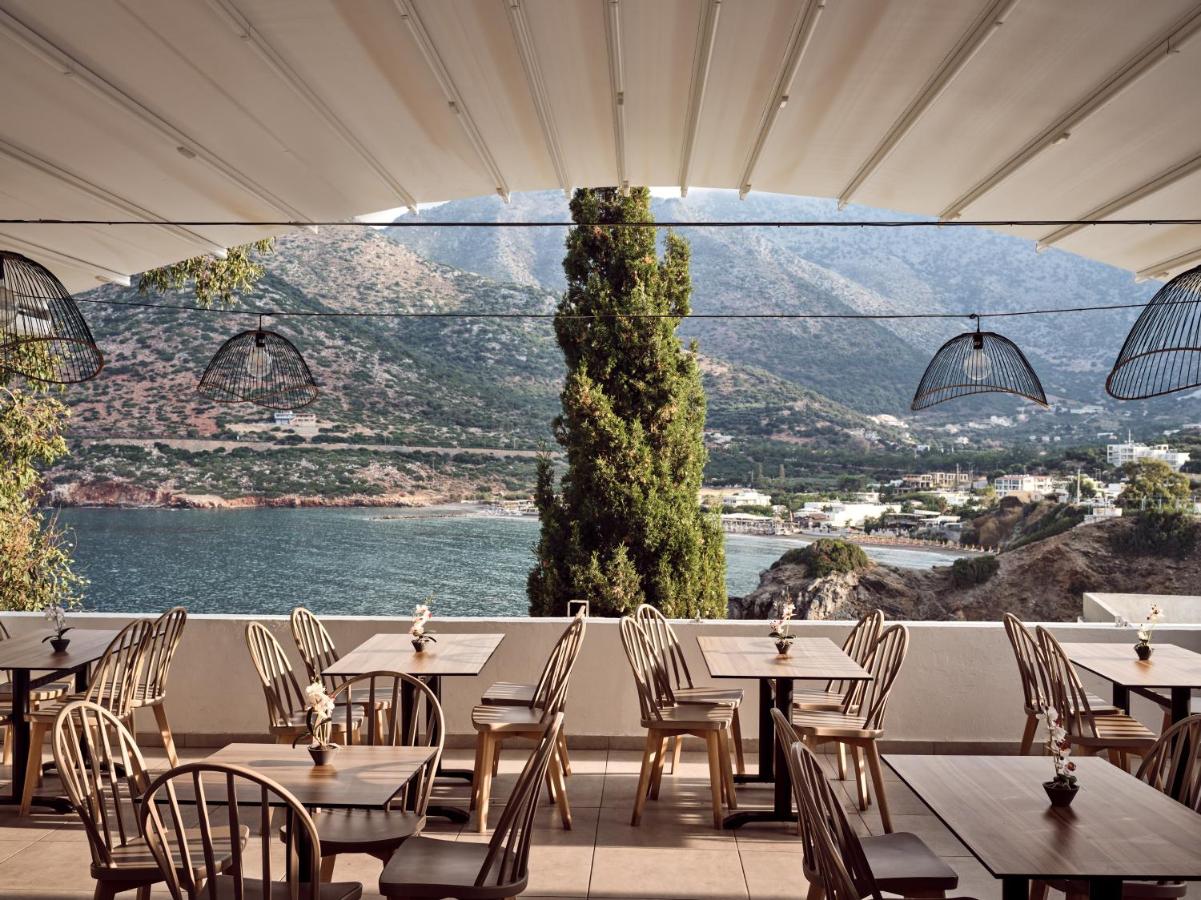 een restaurant met tafels en stoelen en uitzicht op het water bij Troulis Apart-Hotel in Balíon