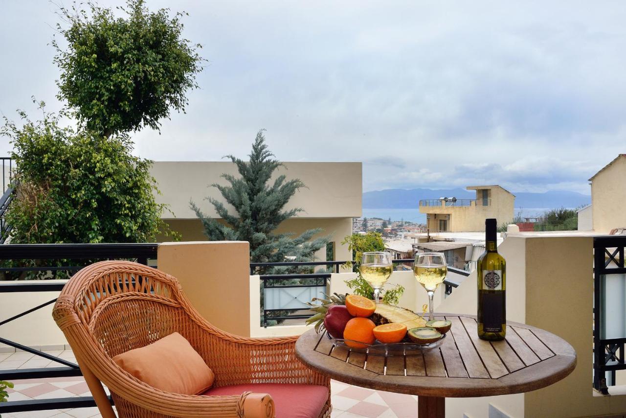 een tafel met glazen wijn en fruit op een balkon bij Mythos- Platanias- Hotel -Apts in Plataniás