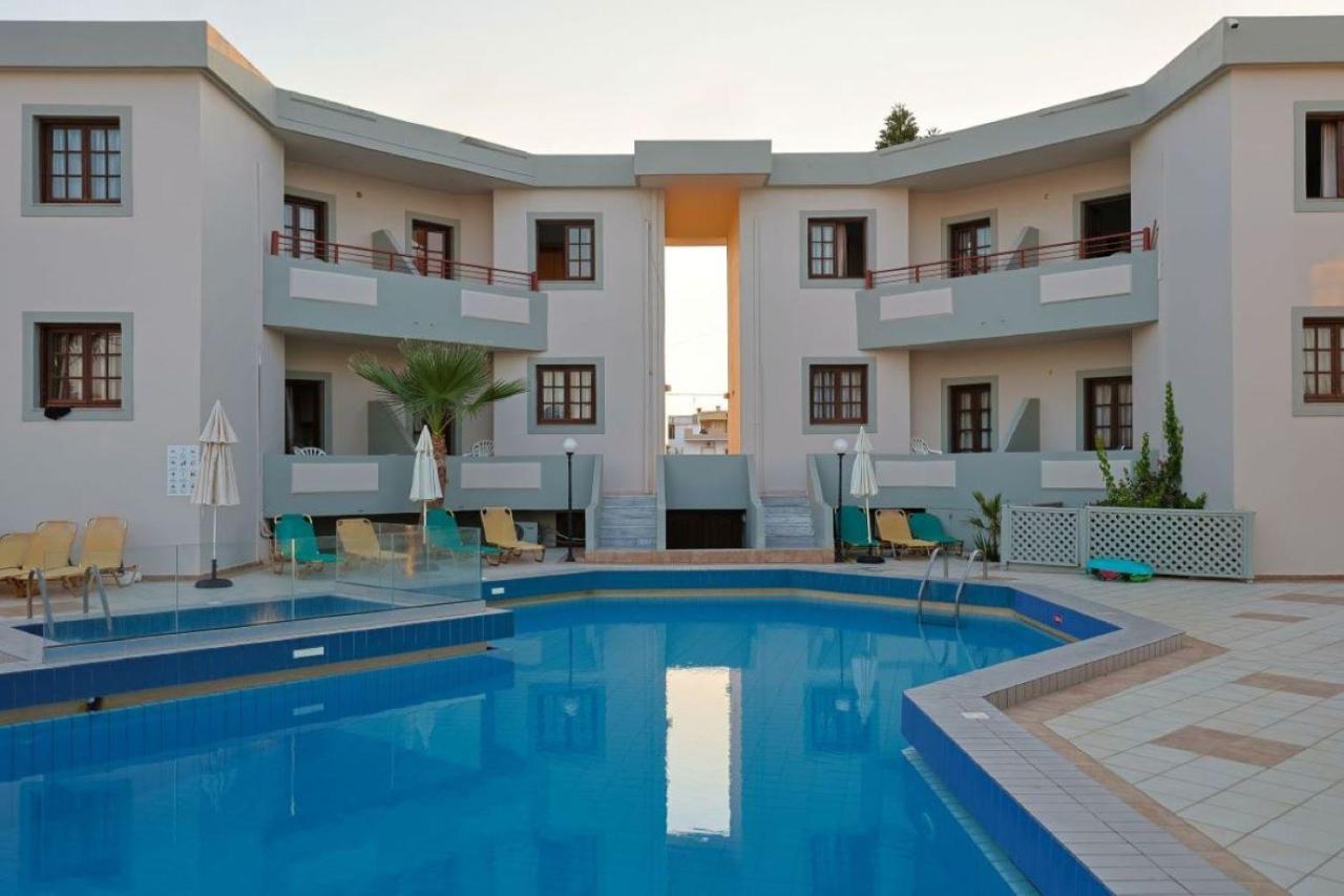een hotel met een zwembad voor een gebouw bij John Mary Apartments by Estia in Gouves