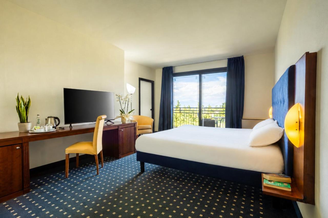 een hotelkamer met een bed, een bureau en een televisie bij Hotel Villa Maria in Desenzano del Garda