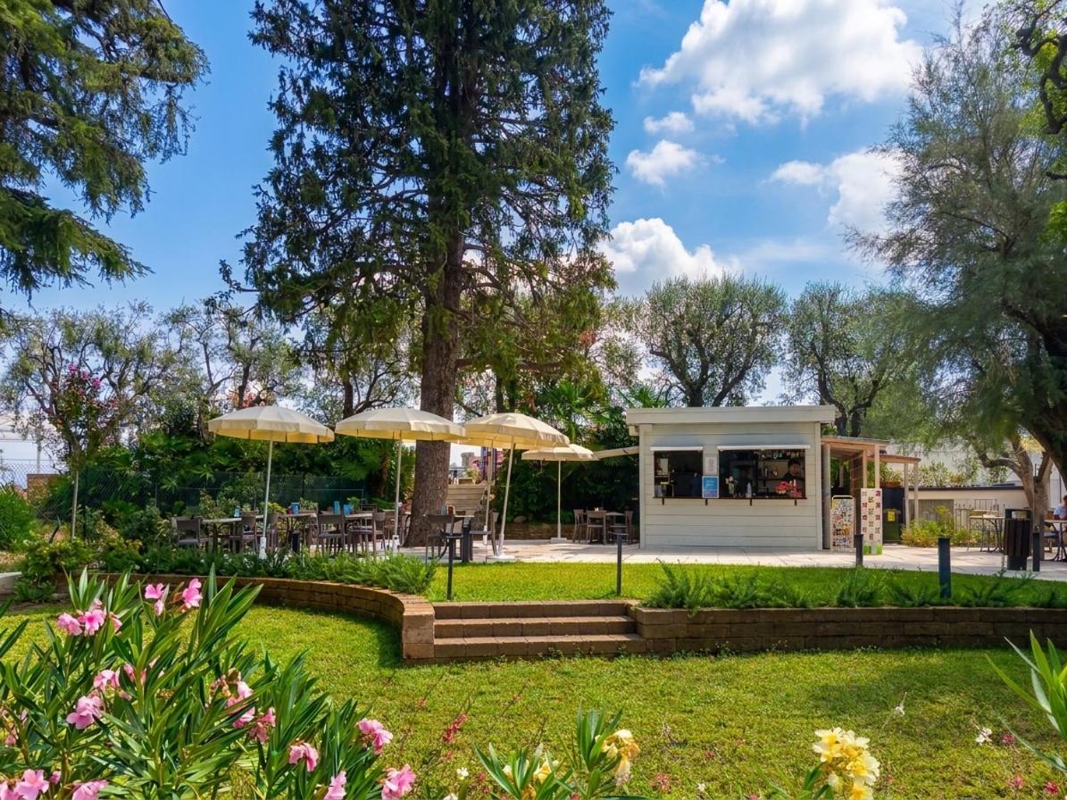 een café met parasols in een park bij Hotel Villa Maria in Desenzano del Garda
