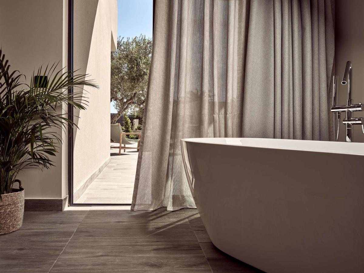 een badkamer met een badkuip en een groot raam bij Numo Ierapetra Beach Resort Crete, Adults only, Curio Collection Hilt