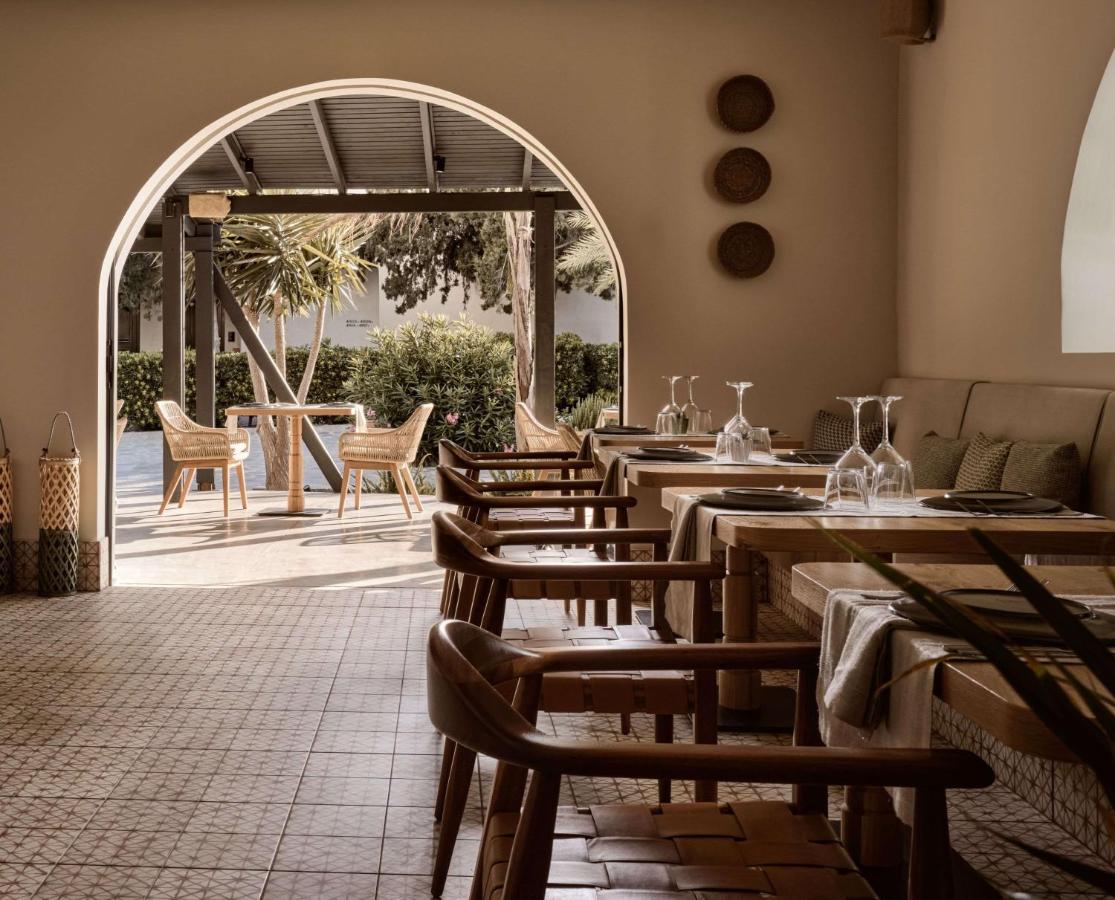 een rij tafels en stoelen in een restaurant bij Numo Ierapetra Beach Resort Crete, Adults only, Curio Collection Hilton 