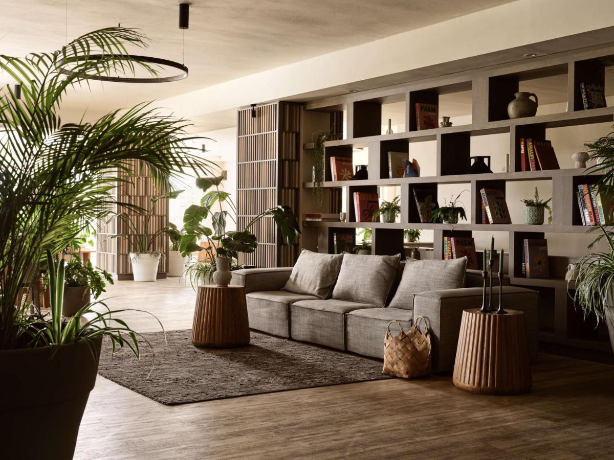 een woonkamer met een bank en veel planten bij Numo Ierapetra Beach Resort Crete, Adults only, Curio Collection Hilton i