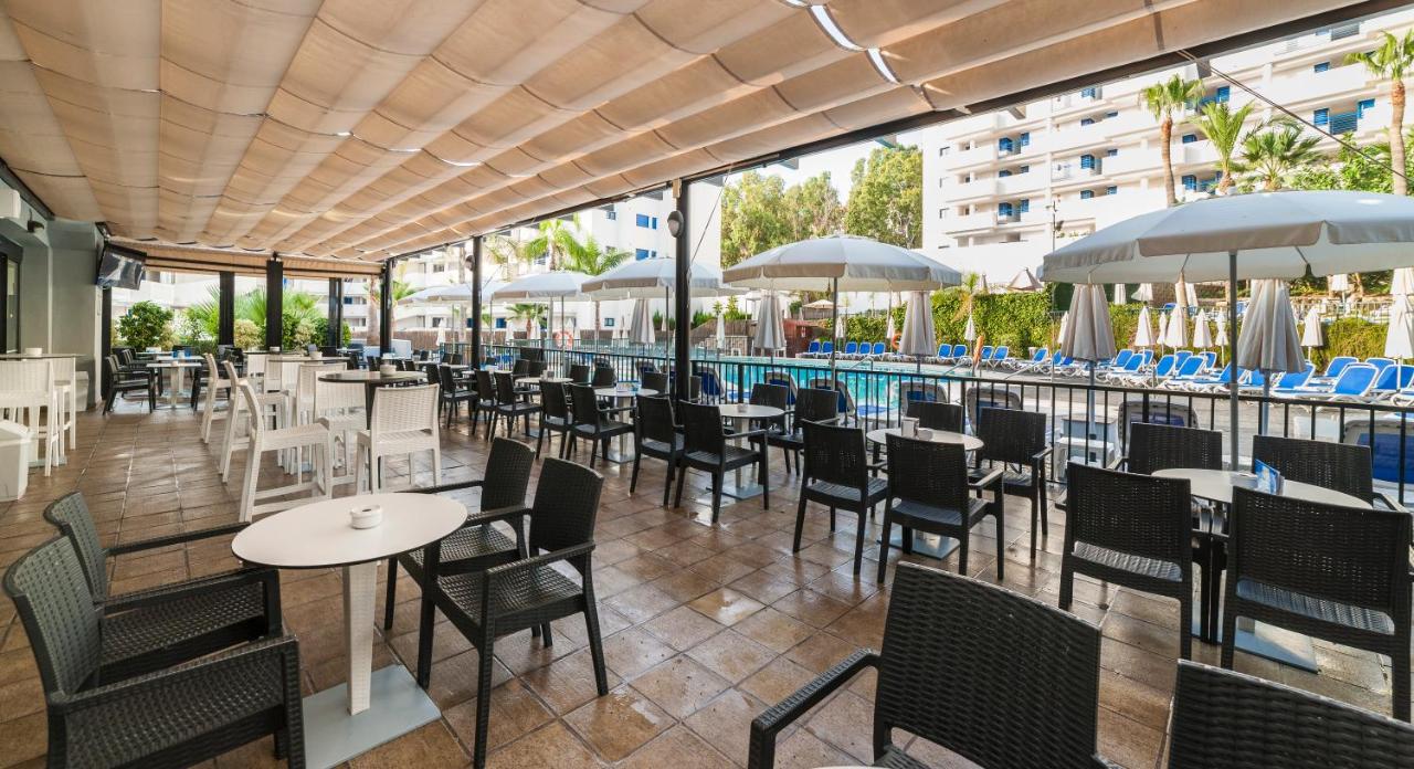 een restaurant met tafels en stoelen en een zwembad bij Globales Los Patos Park in Benalmádena
