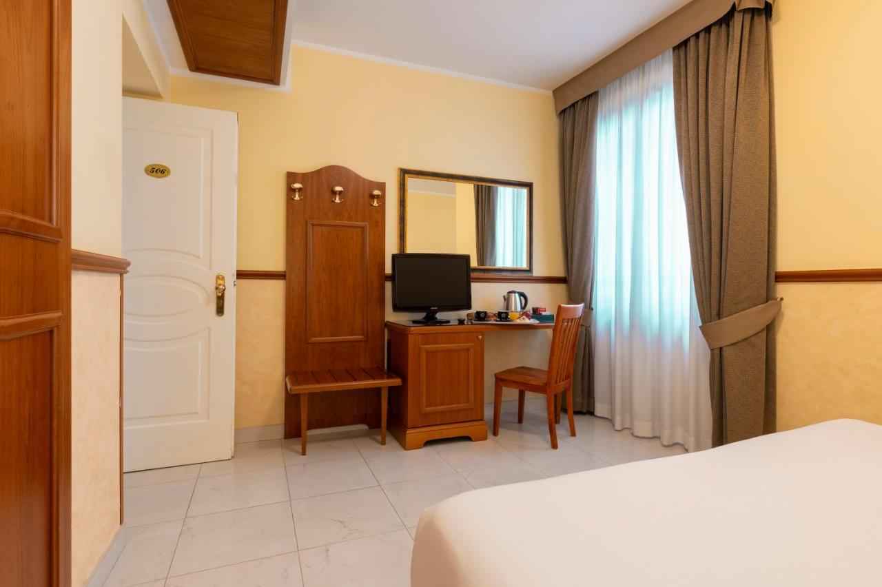een slaapkamer met een bed en een bureau met een televisie bij Hotel Virgilio in Rome