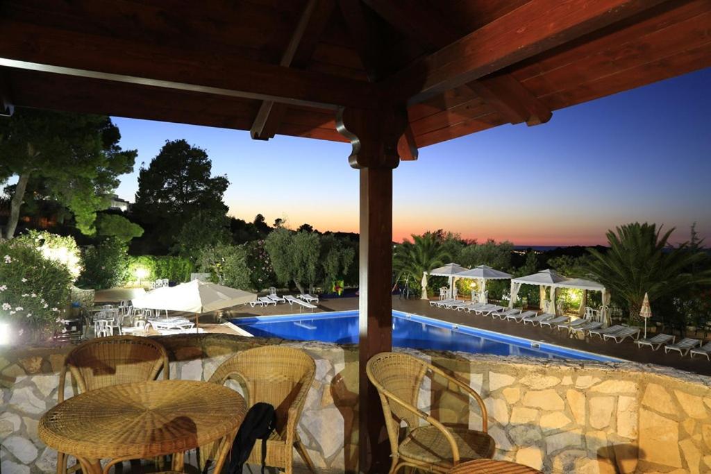 een terras met een tafel en stoelen en een zwembad bij Hotel Club Bellavista in Vieste