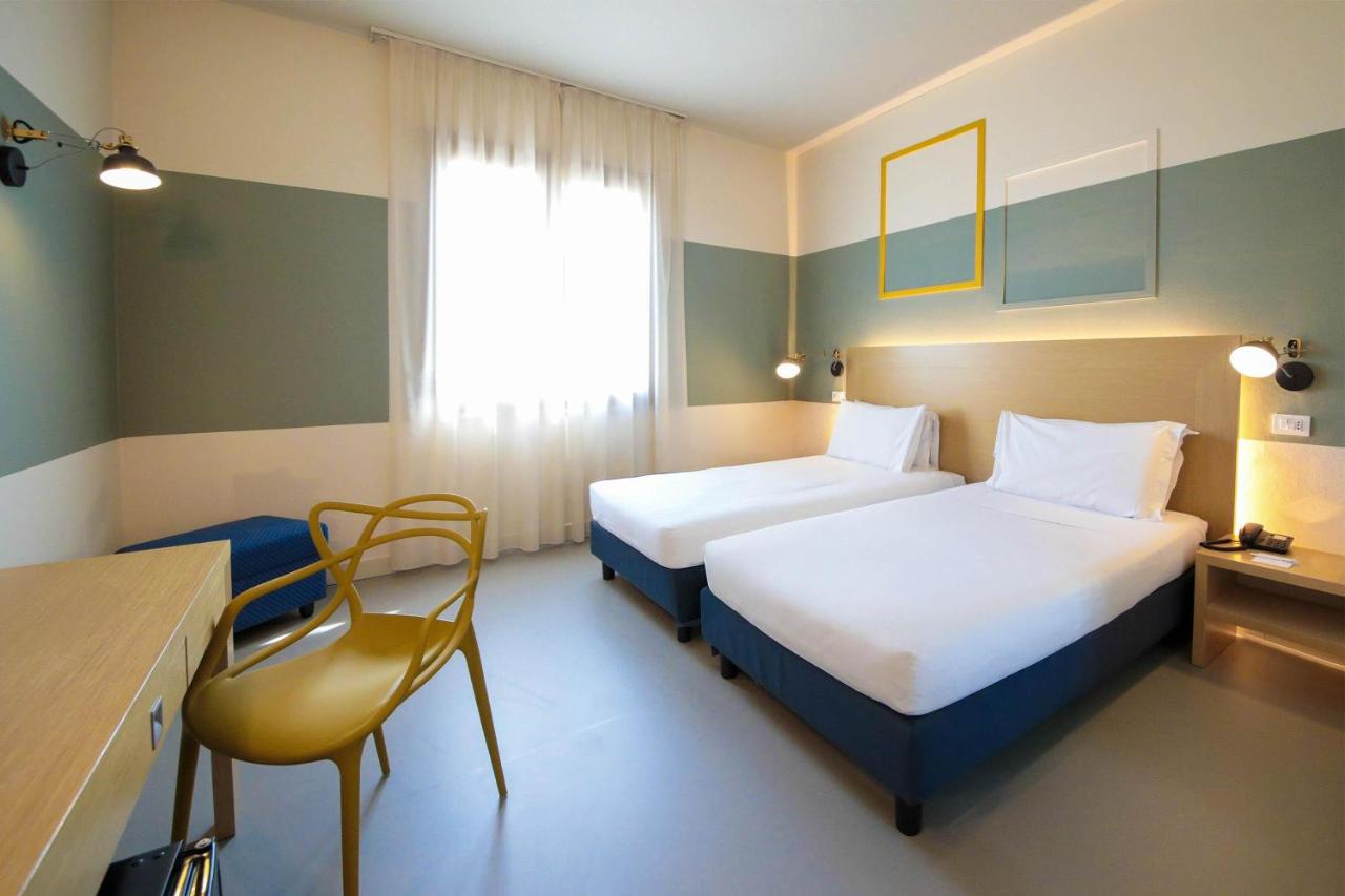 een hotelkamer met twee bedden en een stoel bij B&B HOTEL Mantova Cristallo in Virgilio