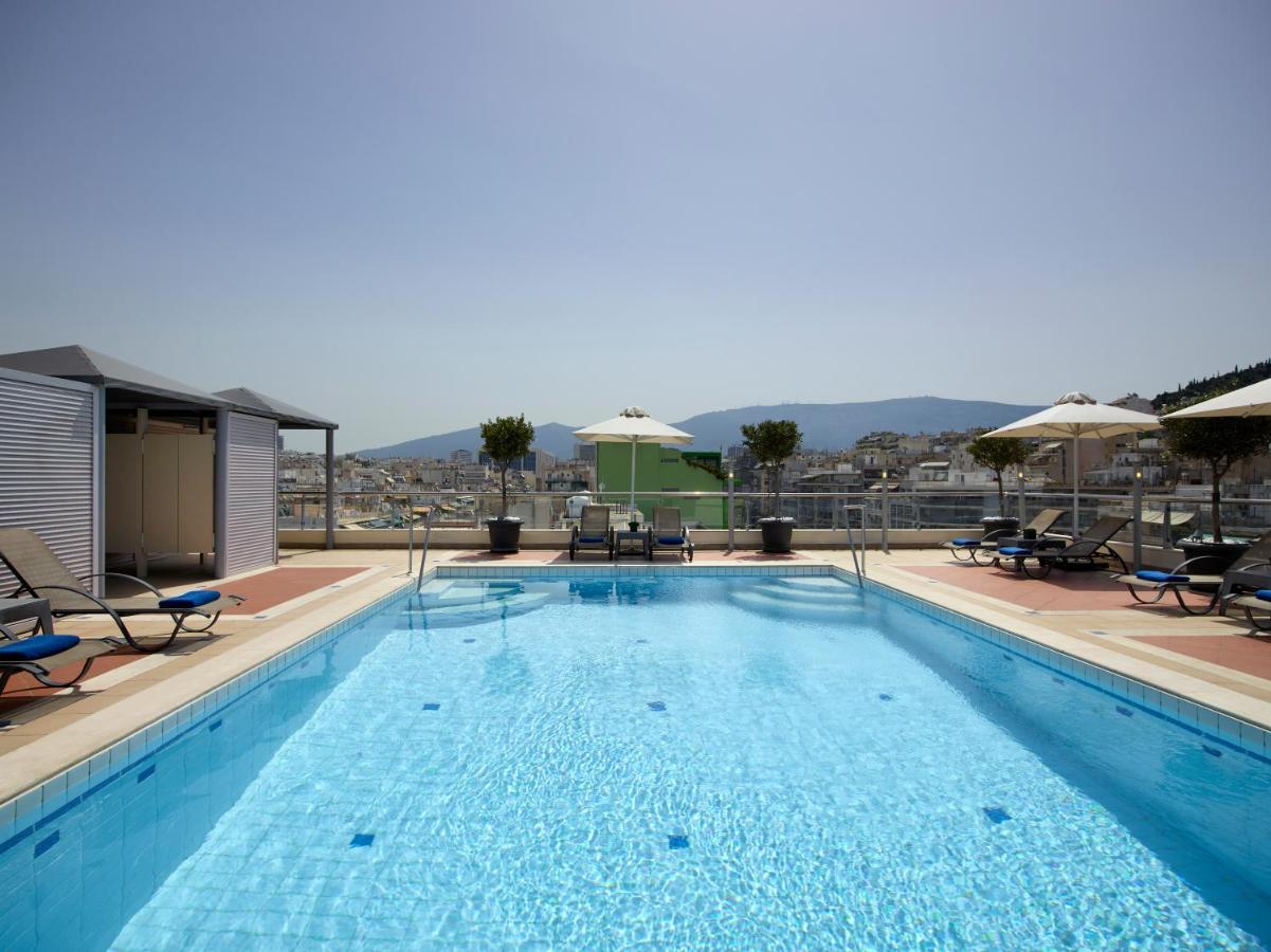 een groot zwembad met ligstoelen en parasols bij Athens Zafolia Hotel in Athene
