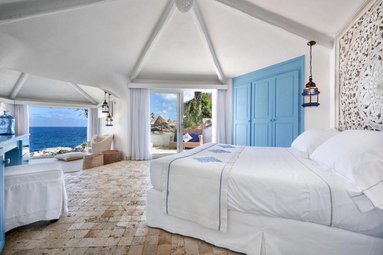 een slaapkamer met een bed en uitzicht op de oceaan bij Arbatax Park Resort - Dune by Falkensteiner in Àrbatax
