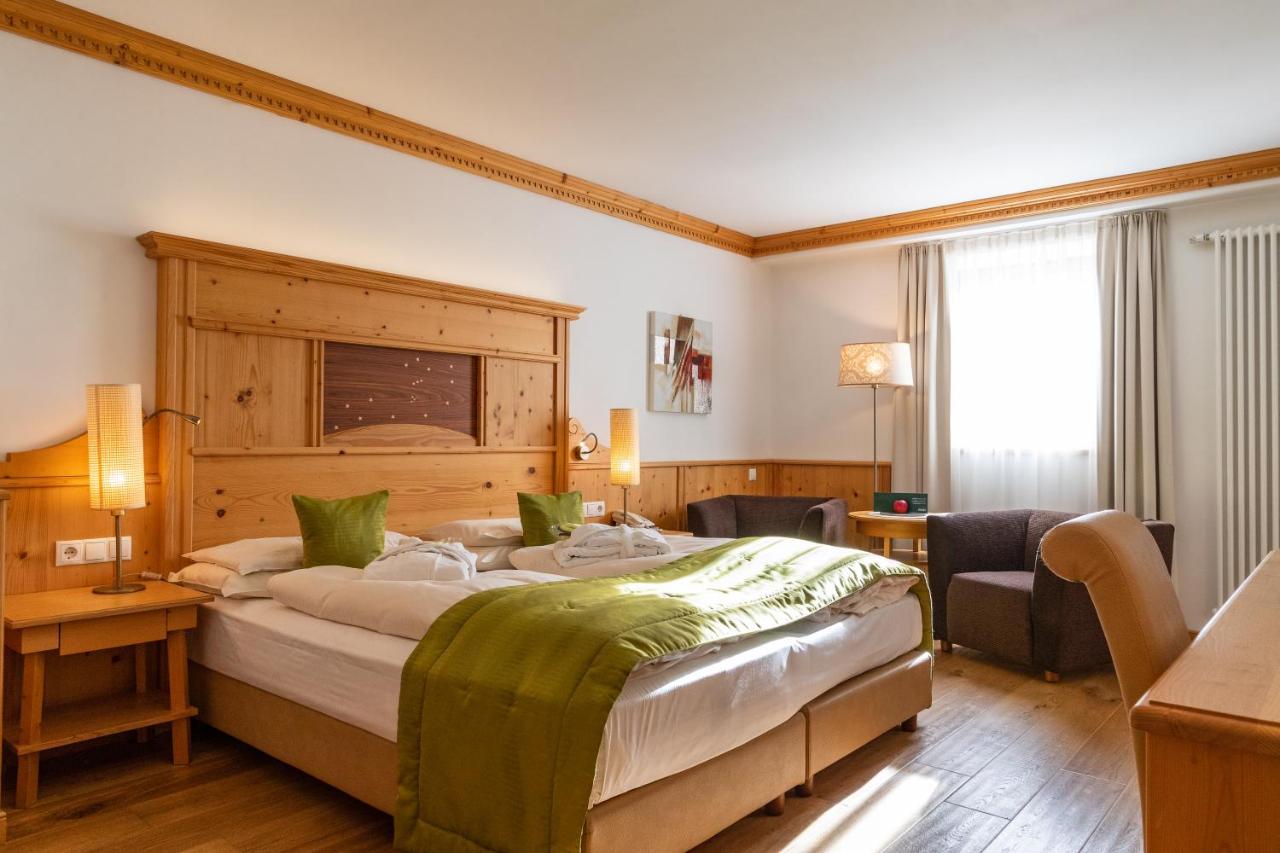 een slaapkamer met een groot bed met een houten hoofdbord bij Vitalhotel Dosses in Santa Cristina in Val Gardena
