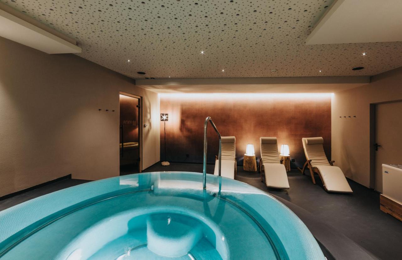 een jacuzzi in een hotelkamer met stoelen bij Vitalhotel Dosses in Santa Cristina in Val Gardena