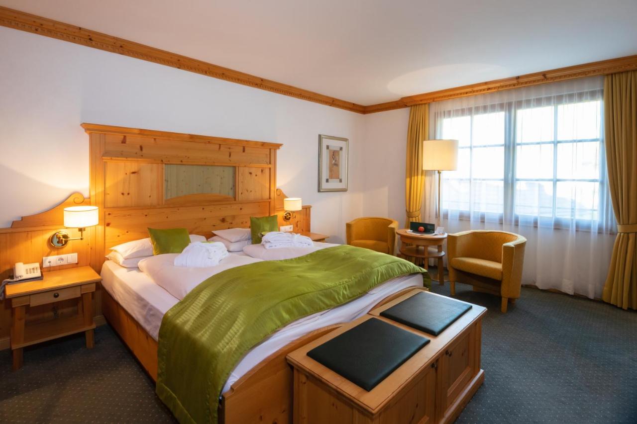 een slaapkamer met een groot bed met een groene deken bij Vitalhotel Dosses in Santa Cristina in Val Gardena